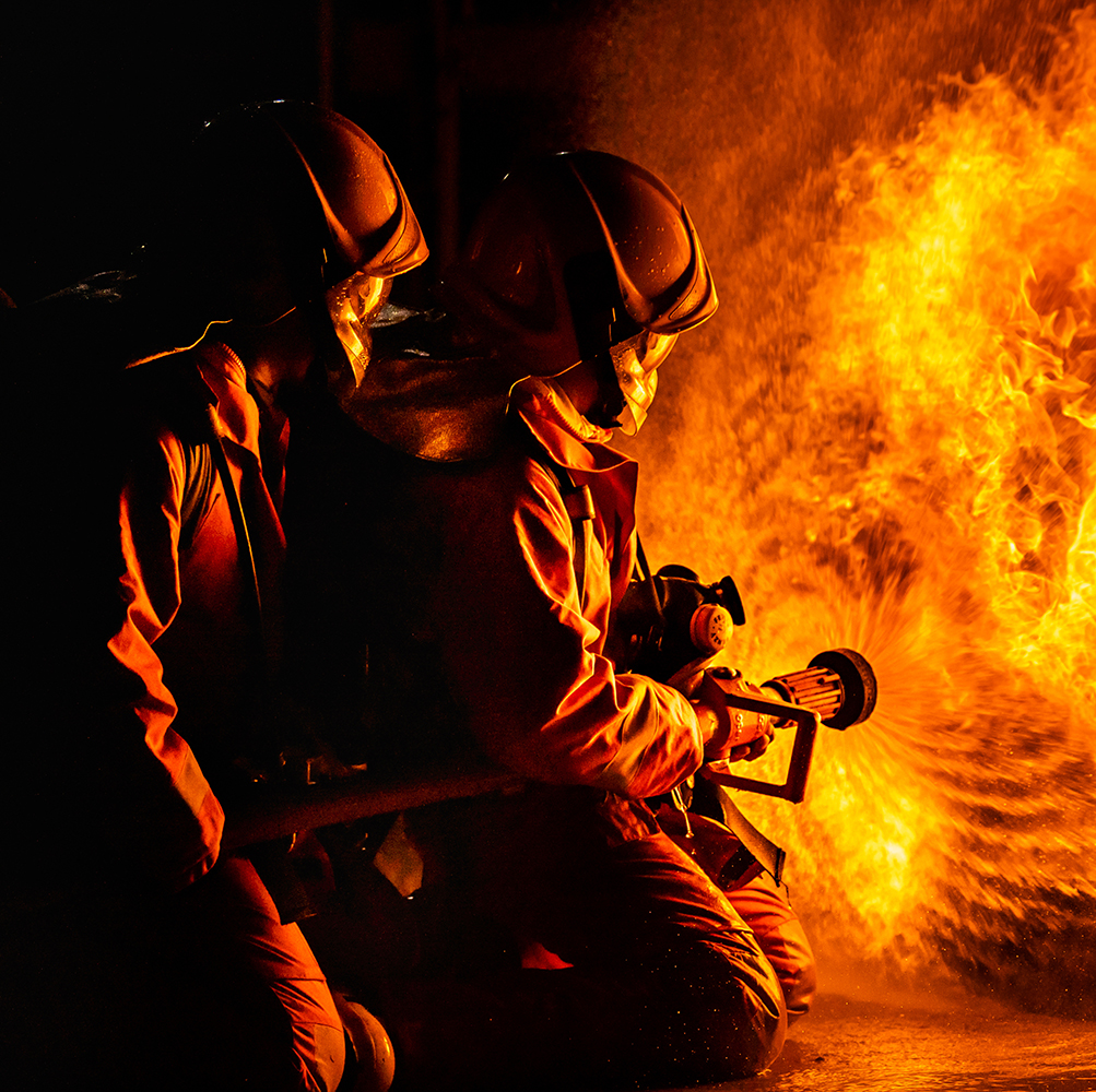 Panoramic firefighters using Twirl water fog type fire extinguisher to fighting with the fire flame from oil to control fire not to spreading out. Firefighter and industrial safety concept.