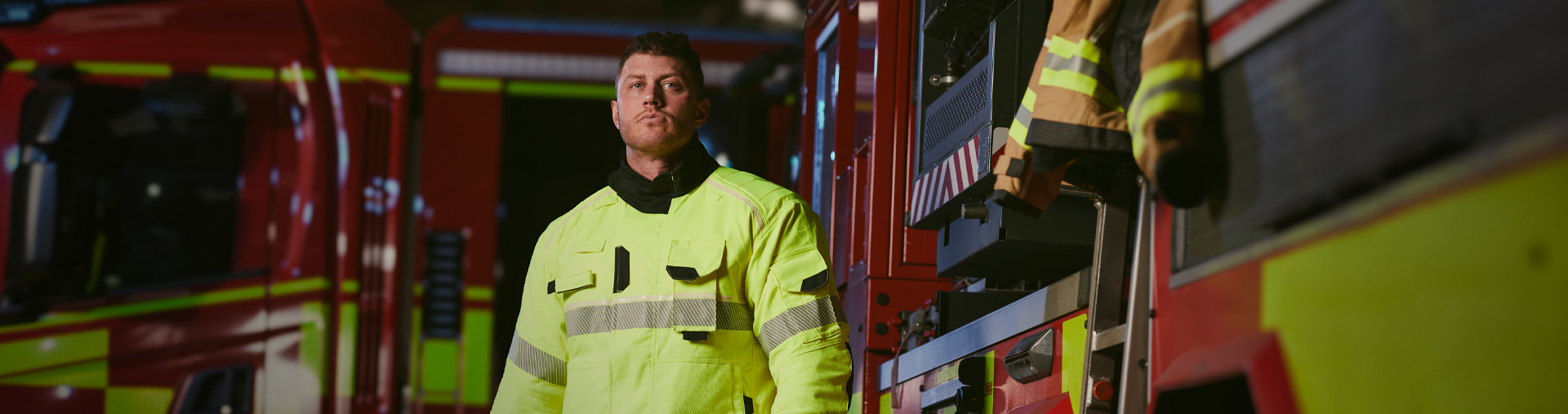 Firefighter stood in front of a firetruck Image - Landscape - 1920x507