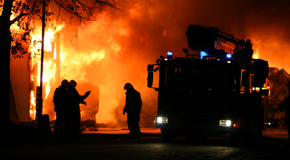 Firefighters tackling a house fire at night - image